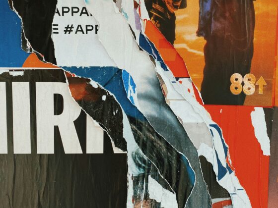 Close-up of a torn collage of colorful posters and paper scraps with visible text fragments and the number 88.