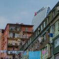Colorful apartment buildings with clothes hanging on lines in the foreground and a large white curved Marriott hotel in the background against a blue sky.