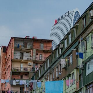 Colorful apartment buildings with clothes hanging on lines in the foreground and a large white curved Marriott hotel in the background against a blue sky.