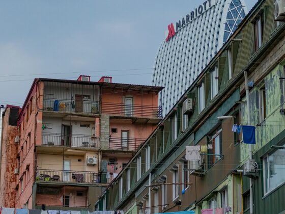 Colorful apartment buildings with clothes hanging on lines in the foreground and a large white curved Marriott hotel in the background against a blue sky.