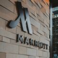 Exterior brick wall with large metallic Marriott logo and the word MARRIOTT beneath it, indicating a hotel entrance.