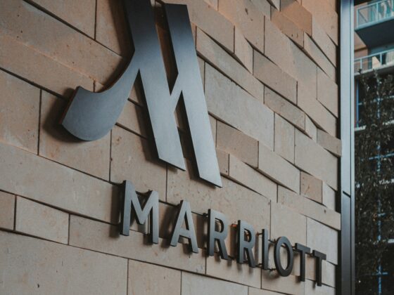 Exterior brick wall with large metallic Marriott logo and the word MARRIOTT beneath it, indicating a hotel entrance.