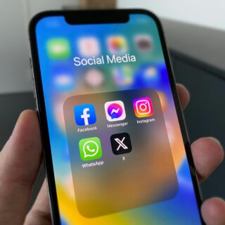 Smartphone screen displaying a folder of social media apps (Facebook, Messenger, Instagram, WhatsApp, X) on a colorful background.