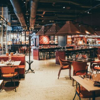 Restaurant dining area with red upholstered chairs, white tables, and warm pendant lighting