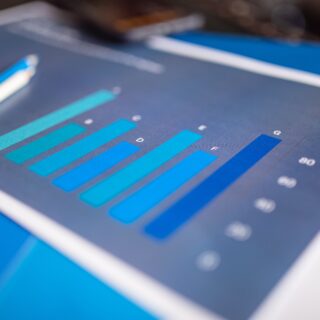Close-up of a tablet screen displaying a blue bar chart with several vertical bars in teal shades.