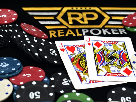 Poker chips in red, black, blue, and green surround two Jack cards on a dark table with a gold RP emblem.