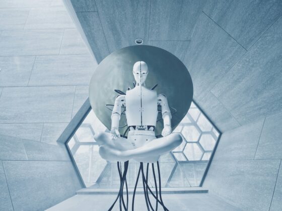 Humanoid robot sculpture seated on a circular pedestal in a blue-tinted glass atrium.