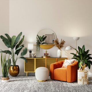 Living room corner with an orange velvet sofa, round mirror above a yellow credenza, and large green plants against a light wall.
