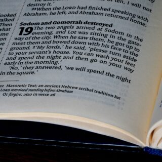 Close-up of a Bible page with a bold heading about Sodom and Gomorrah destroyed, verse 19 visible.