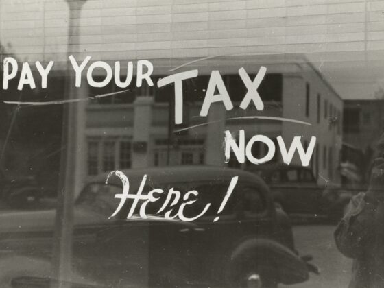 Sign on a window reading 'PAY YOUR TAX NOW' urging viewers to pay taxes now.