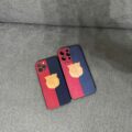 Two iPhones with red and blue cases resting on a gray couch or sofa.