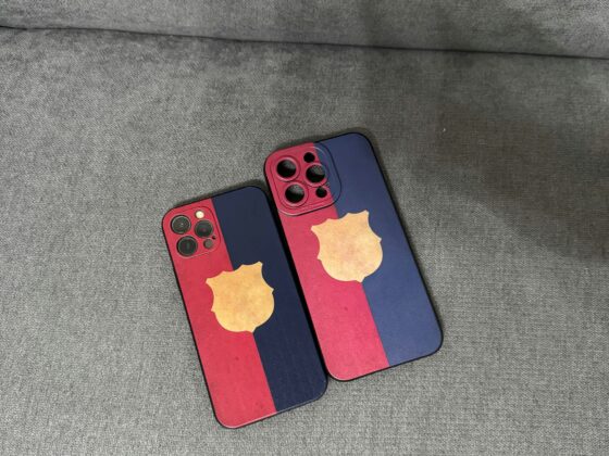 Two iPhones with red and blue cases resting on a gray couch or sofa.