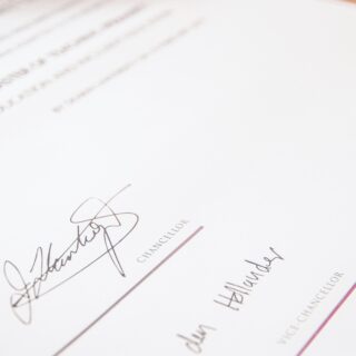 Close-up of a formal document with handwritten signatures and the word CHANCELLOR along the bottom, plus a red circular seal on the right edge.