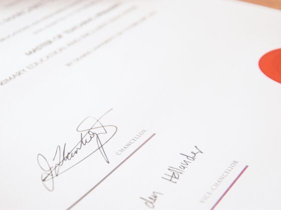 Close-up of a formal document with handwritten signatures and the word CHANCELLOR along the bottom, plus a red circular seal on the right edge.