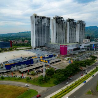 Aerial view of a large shopping complex with an IKEA store in the foreground and tall residential towers in the background.