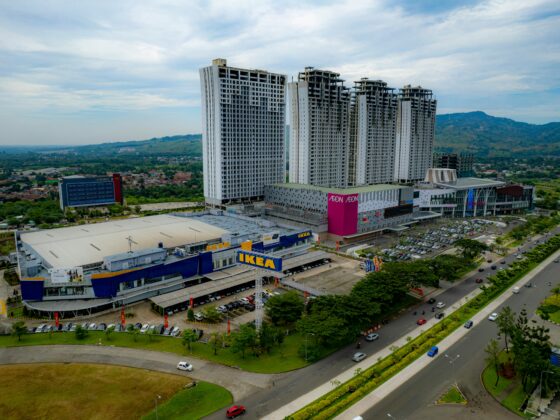 Aerial view of a large shopping complex with an IKEA store in the foreground and tall residential towers in the background.