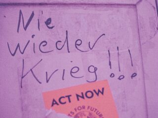 Pink wall with handwritten Polish text and an orange 'ACT NOW' sticker in the corner.
