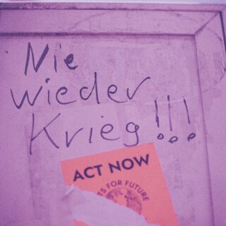 Pink wall with handwritten Polish text and an orange 'ACT NOW' sticker in the corner.