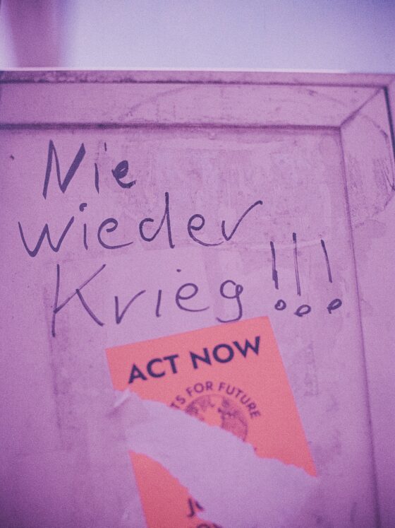 Pink wall with handwritten Polish text and an orange 'ACT NOW' sticker in the corner.