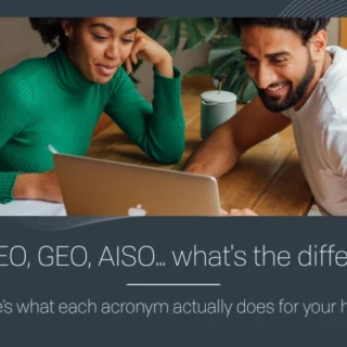 Two colleagues lean over a laptop at a wooden table, reviewing a hotel marketing banner that asks, 'SEO, AEO, GEO, AISO… what’s the difference?' with a subtitle about what each acronym does for your hotel.