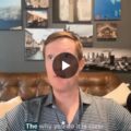 Host in a home studio speaking into a large Shure microphone, with wall art and Skift logo in the corner (GMH podcast).