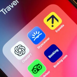 Close-up of a smartphone screen showing travel apps on a pink gradient background: ChatGPT, Skyscanner, Expedia, Booking, and Booking.com icons visible under a 'Travel' label.