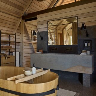 Rustic wooden bathroom with a circular soaking tub, black fixtures, and a large mirror.
