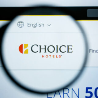 Magnifying glass over a computer screen highlighting the Choice Hotels logo with 'Find a Hotel' in the background and a language option near the top