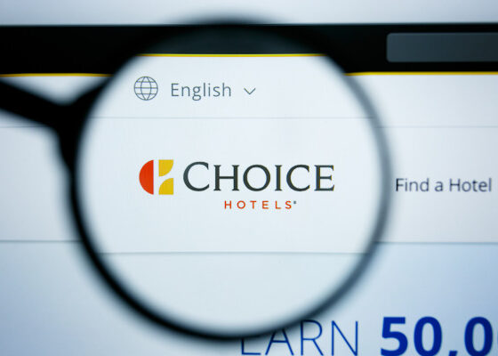 Magnifying glass over a computer screen highlighting the Choice Hotels logo with 'Find a Hotel' in the background and a language option near the top