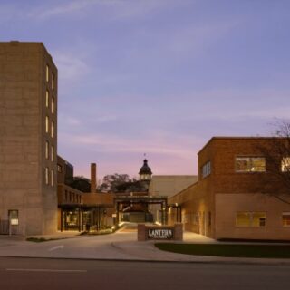 Evening view of a campus entrance with brick buildings on both sides and a sign reading Lantern at the gate.