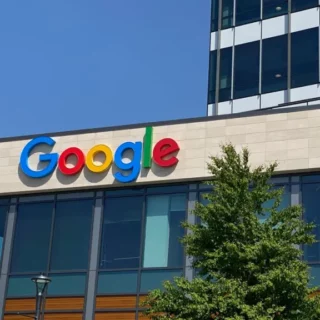 Google logo on the facade of a modern office building under a clear blue sky