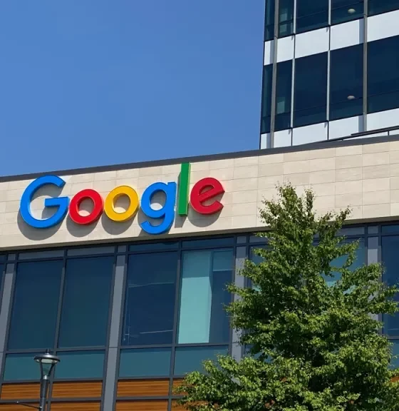 Google logo on the facade of a modern office building under a clear blue sky