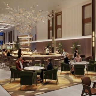 Luxurious hotel lounge with a central bar, chandelier, and groups of guests seated at tables and on green chairs.