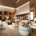 Luxurious hotel lobby with light wood floors, teal rounded chairs, and warm ambient lighting.