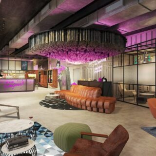Modern lobby/lounge with purple lighting, a curved brown leather sofa, and a circular chandelier; glass-walled seating area to the right.