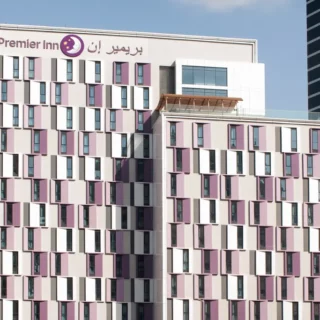 Facade of a multi-story Premier Inn hotel with pink and white window panels and a sign reading 'Premier Inn' at the top.