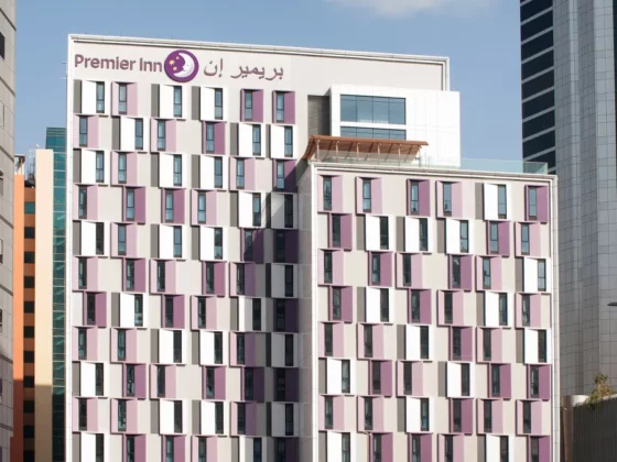 Facade of a multi-story Premier Inn hotel with pink and white window panels and a sign reading 'Premier Inn' at the top.