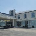 Two-story beige commercial building with arched windows and a covered drop-off area at the entrance.