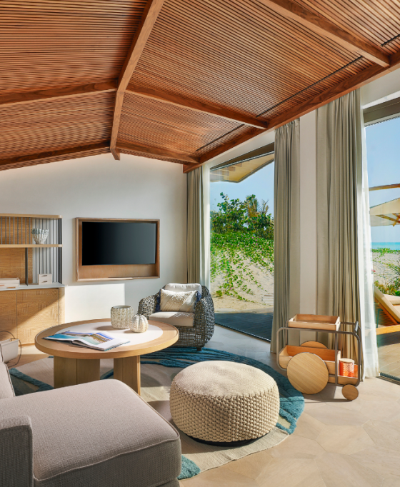Luxurious living room with a wooden vaulted ceiling opening to a beachside view and pool outside