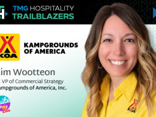 Portrait of Kim Wootteon, Sr. VP of Commercial Strategy at Kampgrounds of America, wearing a yellow shirt at a conference banner