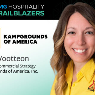Portrait of Kim Wootteon, Sr. VP of Commercial Strategy at Kampgrounds of America, wearing a yellow shirt at a conference banner