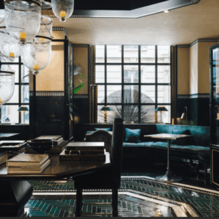 Luxurious hotel lobby or lounge with glass chandelier fixtures, dark wood, and emerald-green seating by large windows.
