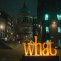 Night city street at night with St. Paul’s Cathedral in the distance and a large orange 'Liverpool' sign in the foreground.