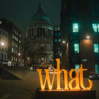 Night city street at night with St. Paul’s Cathedral in the distance and a large orange 'Liverpool' sign in the foreground.