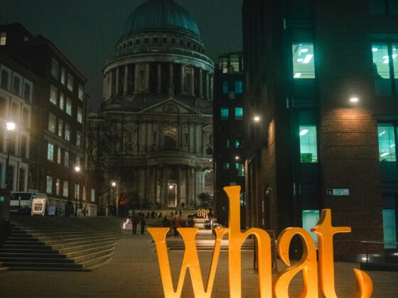 Night city street at night with St. Paul’s Cathedral in the distance and a large orange 'Liverpool' sign in the foreground.