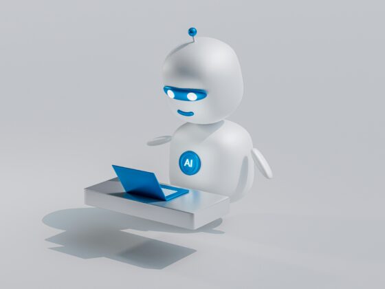 White robot with blue visor and AI badge working at a laptop on a desk