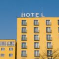 Yellow hotel building with many windows and small balconies under a clear blue sky; HOTEL sign on the roof.