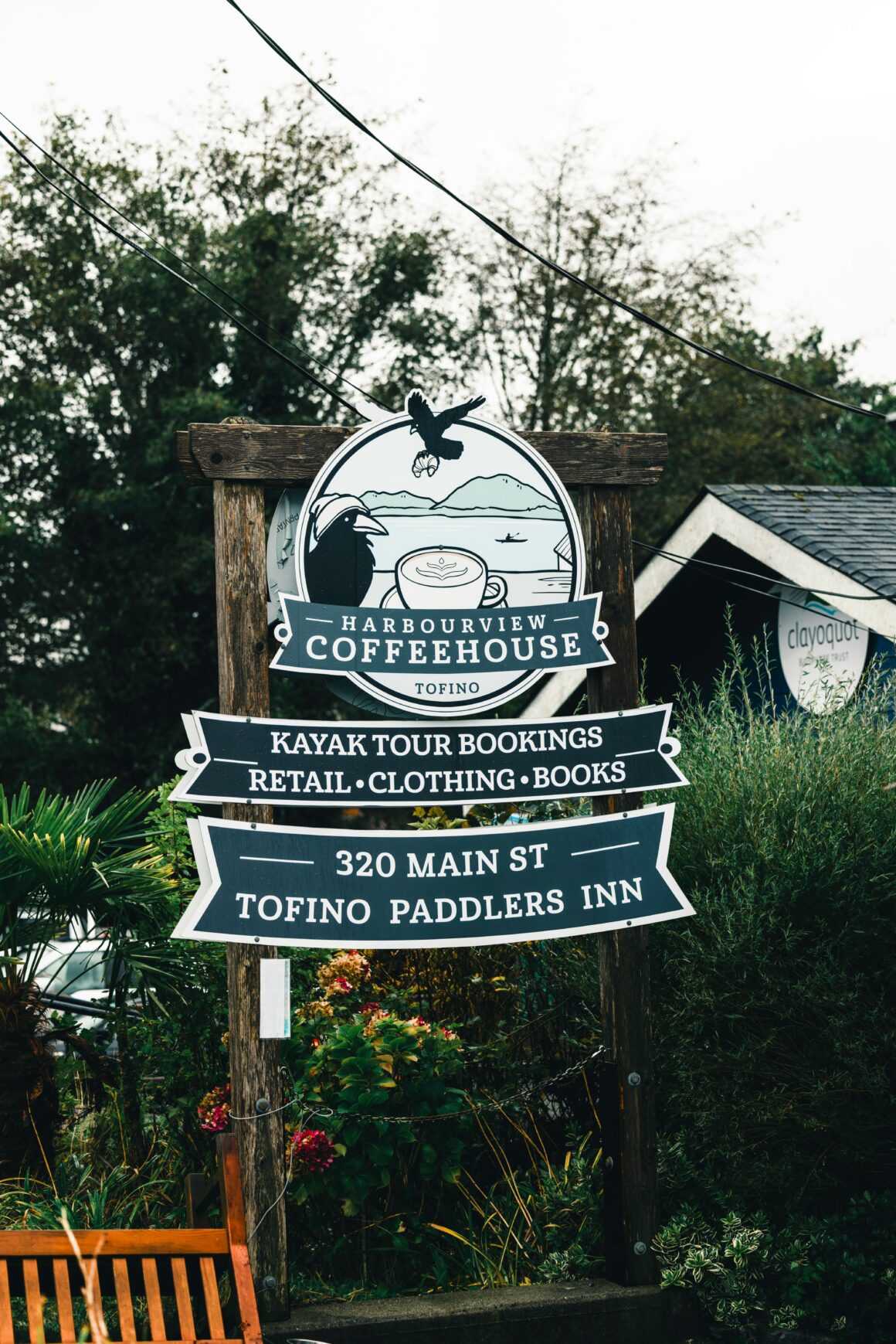 Outdoor wooden sign for Harbourview Coffeehouse in Tofino, advertising kayak tours, retail, clothing and books; 320 Main St.