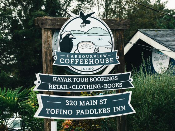 Outdoor wooden sign for Harbourview Coffeehouse in Tofino, advertising kayak tours, retail, clothing and books; 320 Main St.
