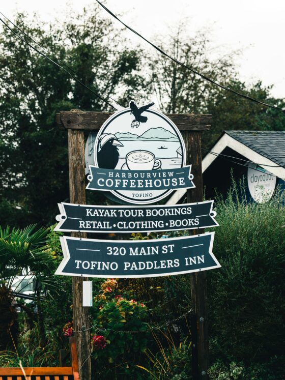 Outdoor wooden sign for Harbourview Coffeehouse in Tofino, advertising kayak tours, retail, clothing and books; 320 Main St.